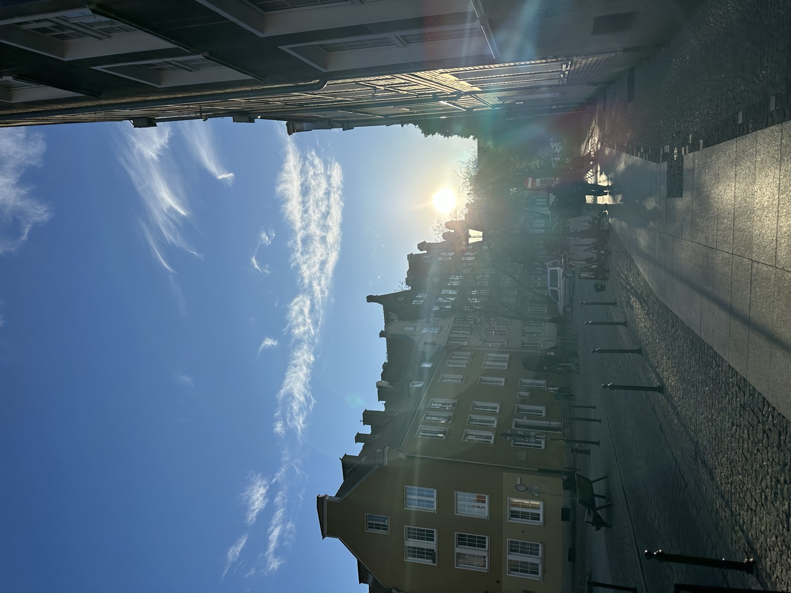 A side street under a sun flare, the camera catching the afternoon light